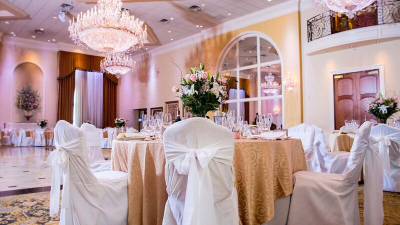 Table with gold cloth and white seat covers in ballroom.